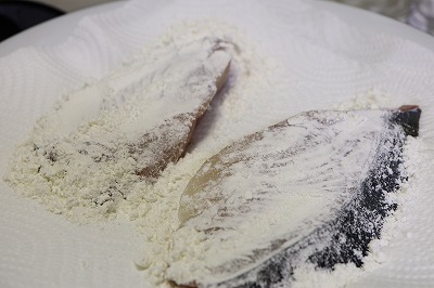 ぶりの切り身に小麦粉をまぶしているところ