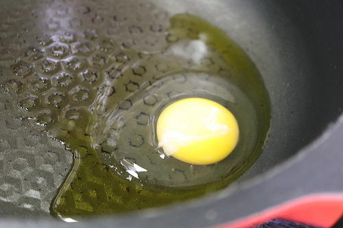 卵をフライパンに落として焼いている